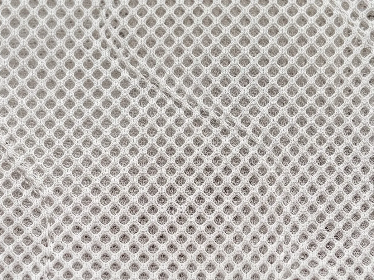 Close view of a pale technical mesh with a regular dotted grid