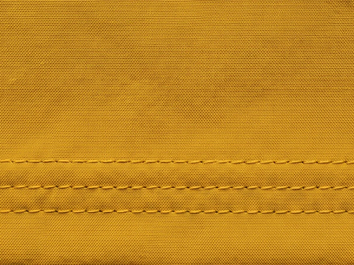 Close view of a saturated mustard fabric face with a stitched seam running through it