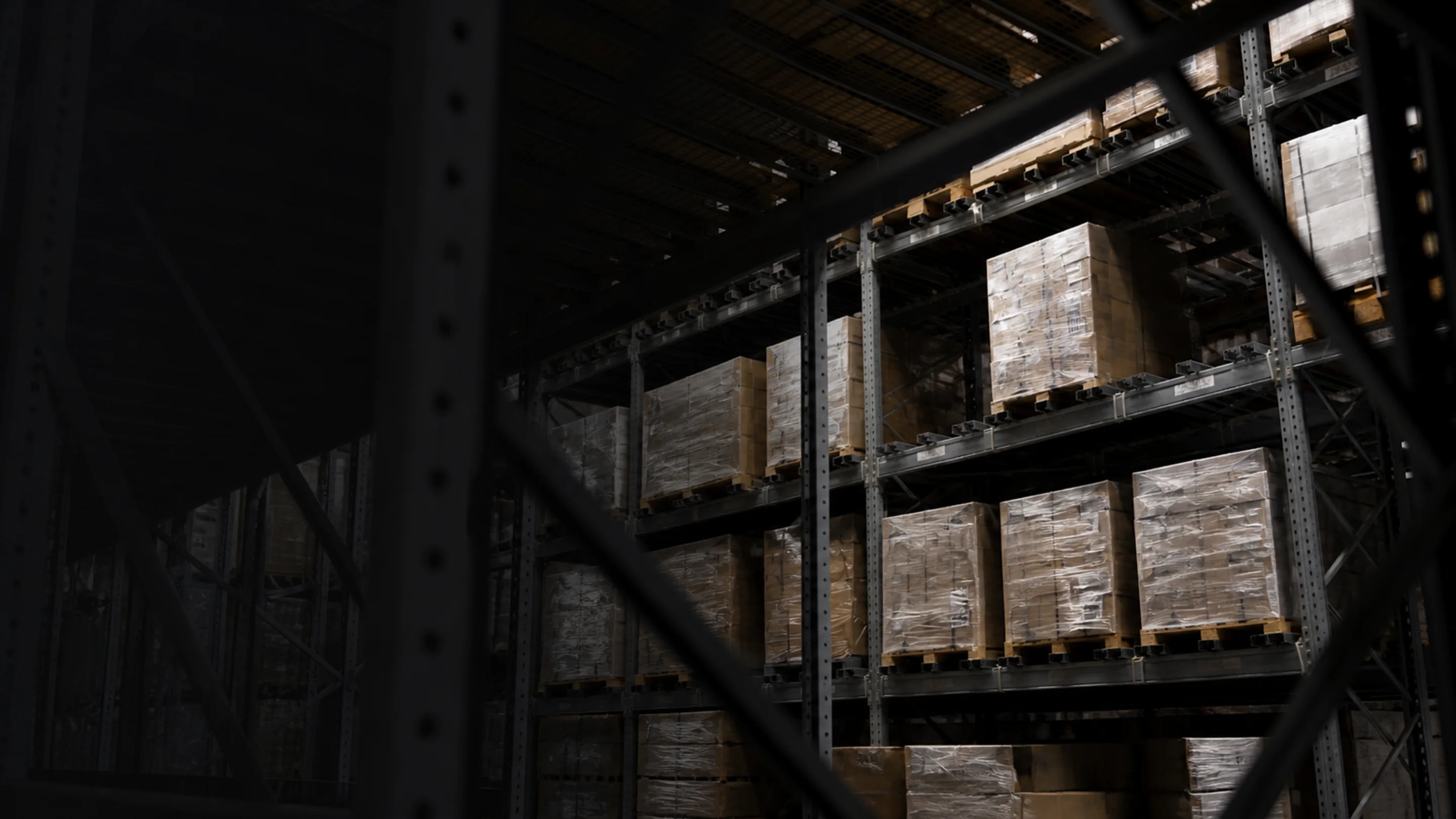 Plastic-wrapped pallets of goods on industrial warehouse racking