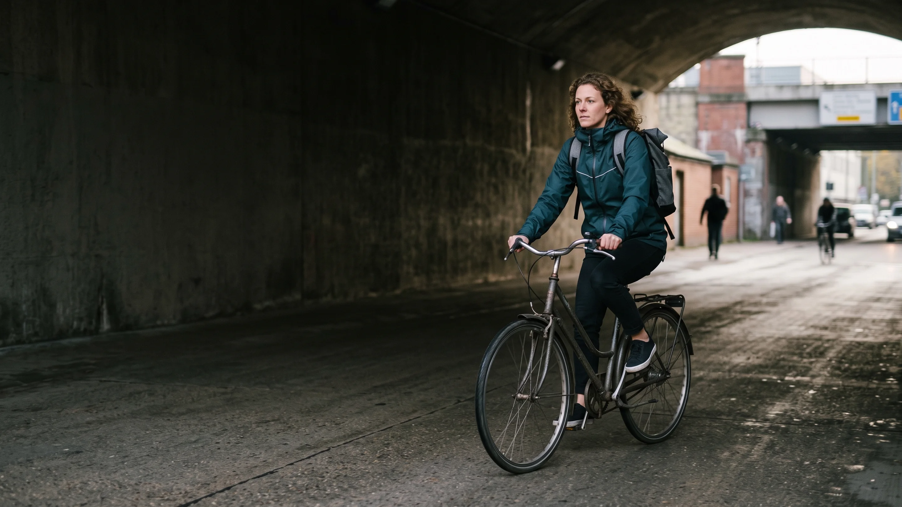 A commuter riding through a city underpass in low morning light
