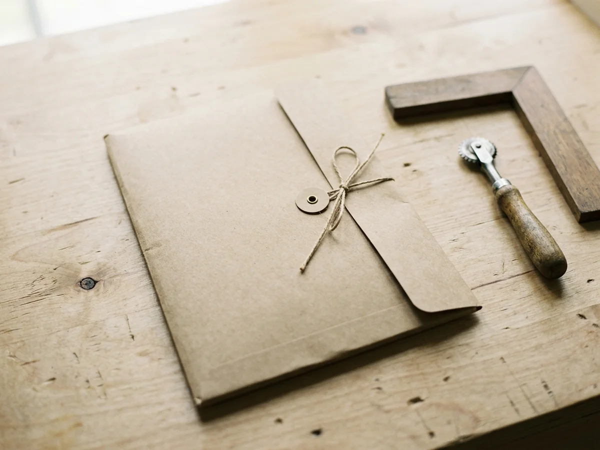 A plain kraft folder lying closed and tied shut on the same table, nothing visible inside