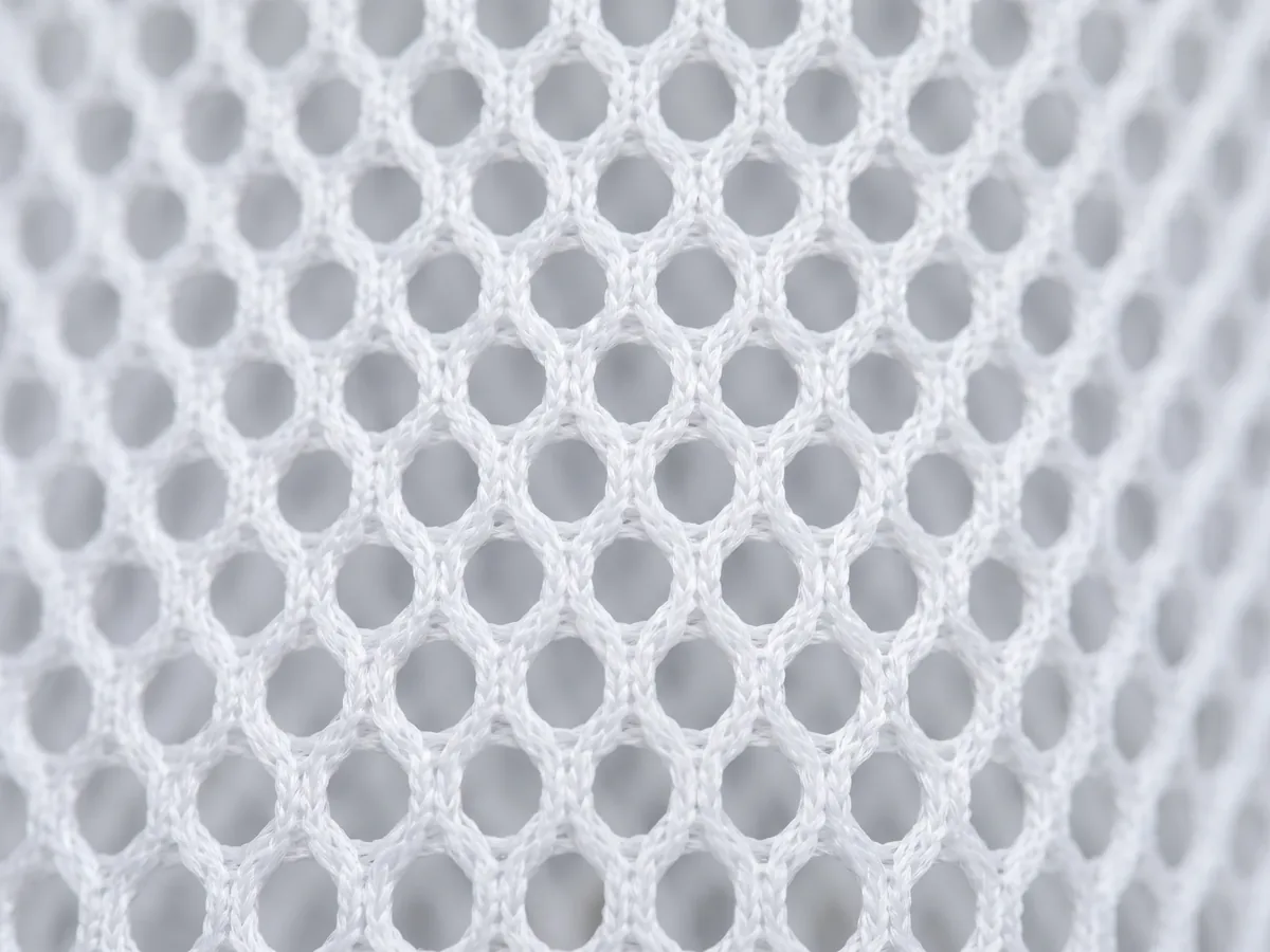 Macro of a white open-structure performance mesh