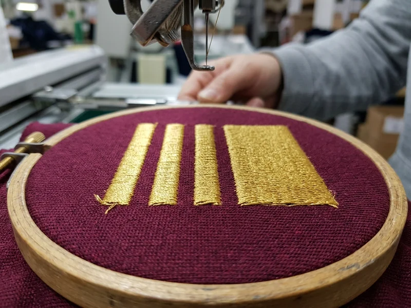 Computerized embroidery machine stitching a club crest onto jersey fabric